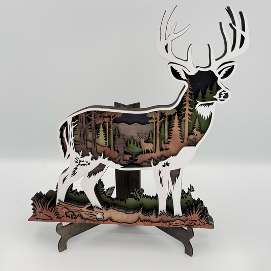 Layered deer silhouette with forest scene