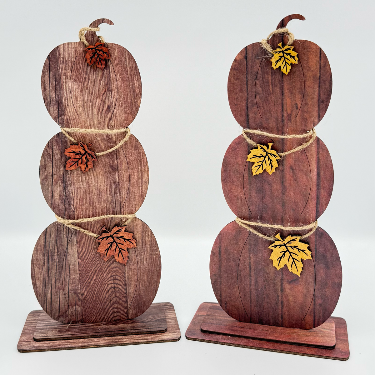 Two stacked wooden pumpkin displays with fall leaves